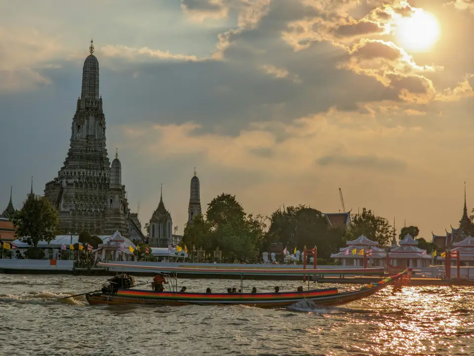 夕陽下船隻開過昭披耶河上的鄭王廟｜<a href="https://unsplash.com/photos/a-boat-sails-past-a-temple-at-sunset-DkGGun8ZwAo" target="_blank" rel="noopener">Unsplash 原圖</a>