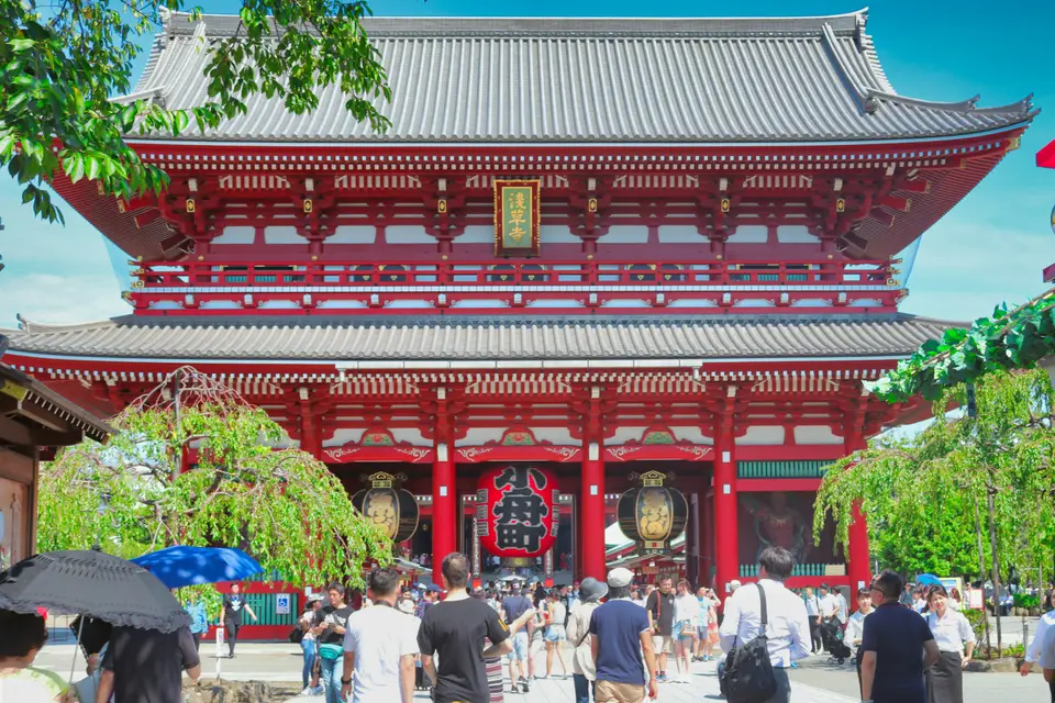 白天的淺草寺正門，遊客來來往往｜<a href="https://unsplash.com/photos/people-walking-on-street-near-red-and-white-building-during-daytime-FDi1rnL3j8g" target="_blank" rel="noopener">Unsplash 原圖</a>